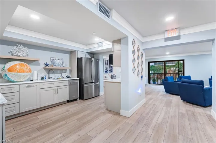 Community Kitchen featuring crown molding, open shelves, stainless steel appliances, light wood finished floors, and open floor plan