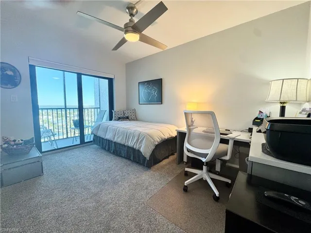 Carpeted bedroom with a desk, access to a balcony that overlooks the boat dock and Bay, and ceiling fan