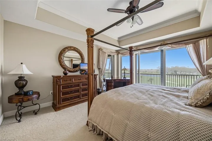 Carpeted bedroom with a raised ceiling, access to exterior, multiple windows, and ornamental molding