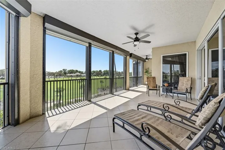 Sunroom / solarium with ceiling fan, a textured ceiling, tile patterned floors, golf course view, and a water view