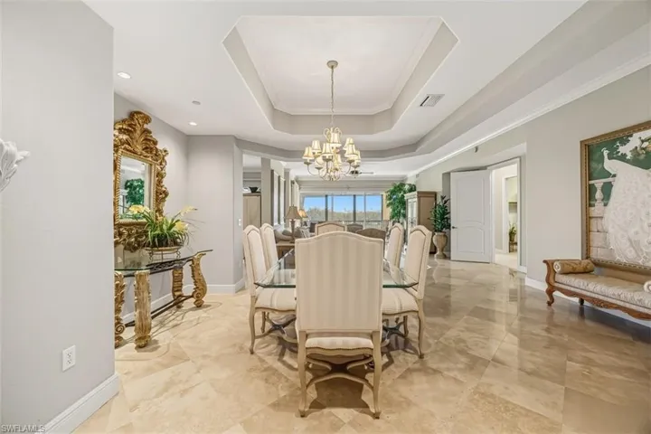Dining space with a tray ceiling, a chandelier, crown molding, and recessed lighting