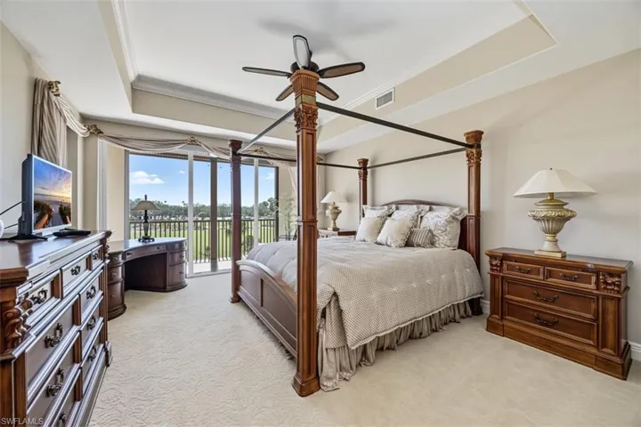 Bedroom with a tray ceiling, light carpet, access to exterior, ornamental molding, and ceiling fan