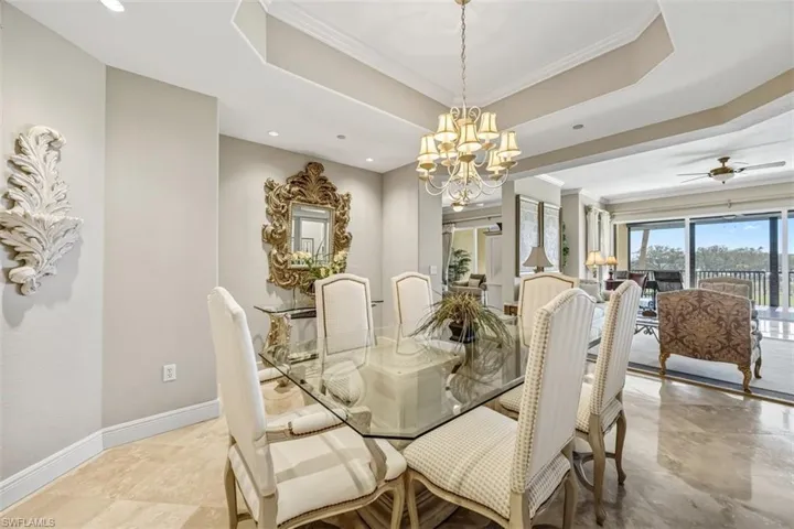 Dining space with a raised ceiling, ornamental molding, a chandelier, and ceiling fan