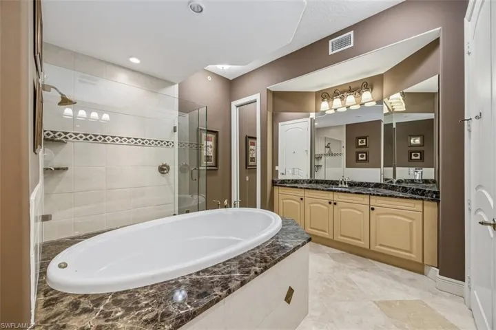 Bathroom with a shower stall, vanity, a garden tub, light tile patterned floors, and recessed lighting