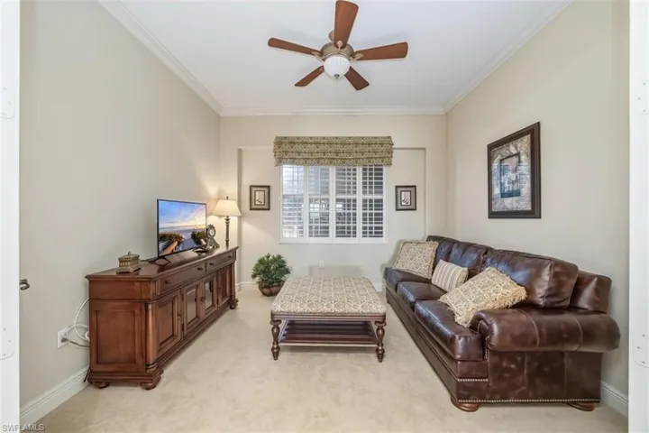 Carpeted living room featuring ornamental molding and a ceiling fan