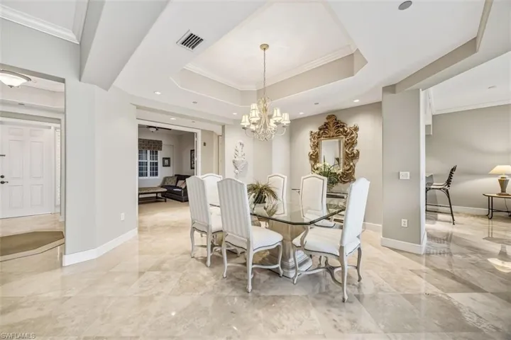 Dining room with ornamental molding, a raised ceiling, and a chandelier