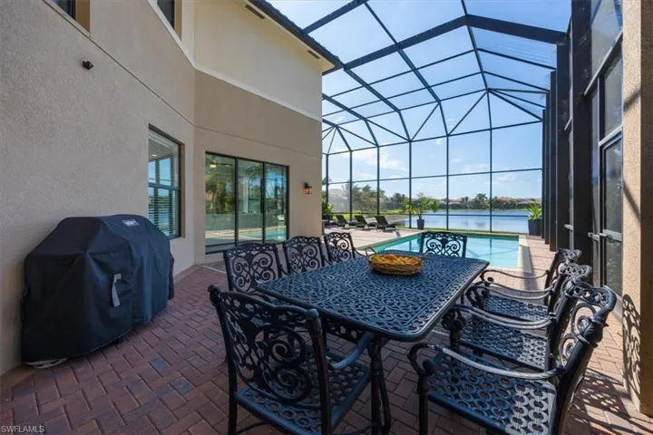 View of patio featuring a grill, glass enclosure, an outdoor pool, and outdoor dining space