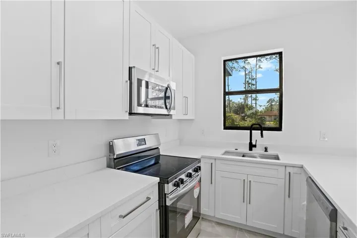 Kitchen featuring white shaker cabinetry, stainless steel appliances, white countertops, a stainless steel sink, and a black gooseneck faucet