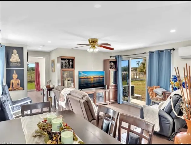 Dining space featuring a wall unit AC, ceiling fan, and hardwood / wood-style flooring