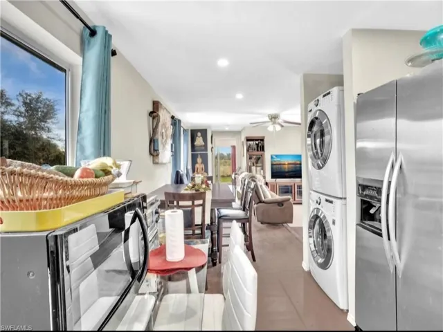 Kitchen featuring stacked washer / drying machine, ceiling fan, and stainless steel fridge with ice dispenser