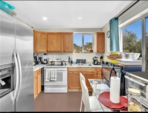Kitchen with stainless steel fridge, sink, and electric stove