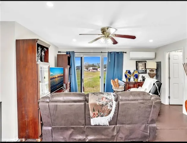 Living room with an AC wall unit and ceiling fan