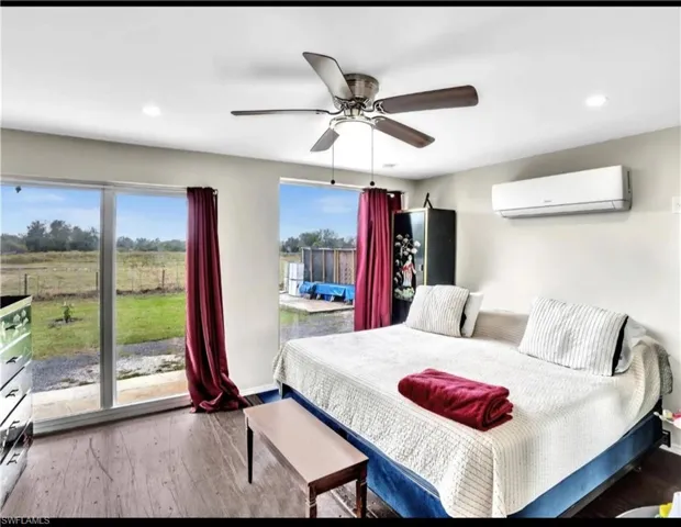 Bedroom with an AC wall unit, multiple windows, hardwood / wood-style floors, and ceiling fan