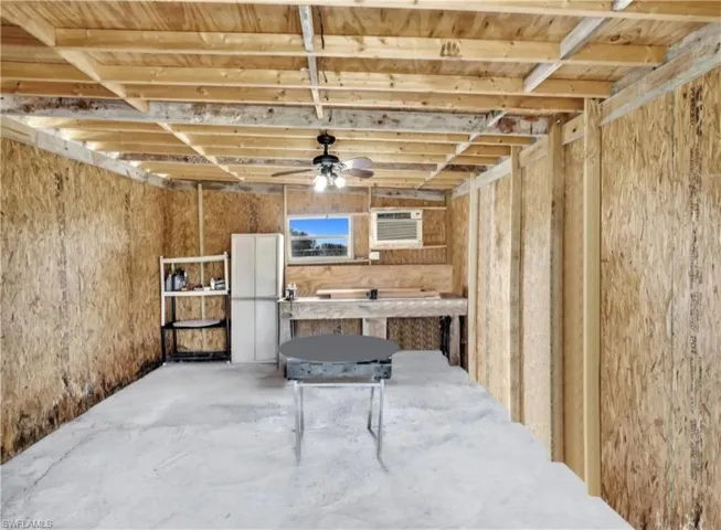 Basement with an AC wall unit and ceiling fan