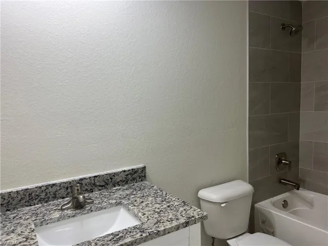 Full bathroom with vanity, tiled shower / bath combo, and toilet