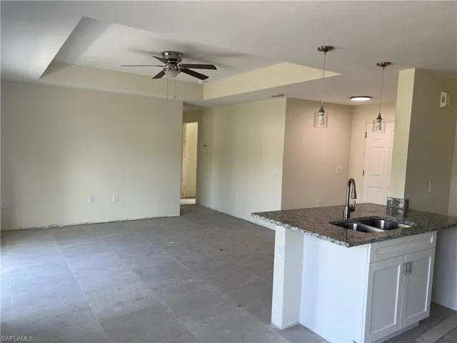 Kitchen with white cabinets, ceiling fan, tile patterned floors, a raised ceiling, and sink