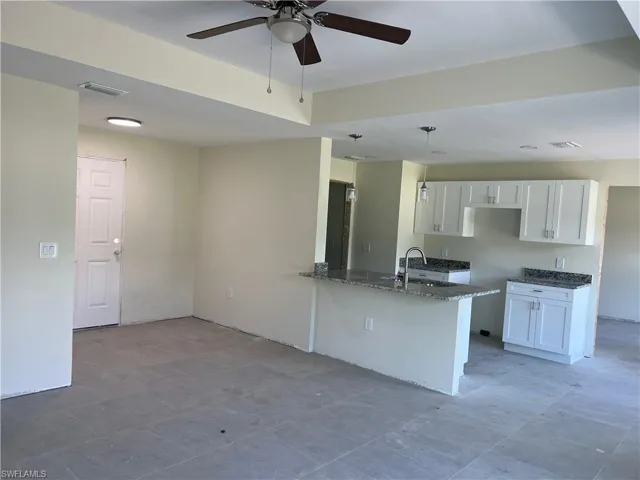 Kitchen with white cabinetry, light tile patterned floors, ceiling fan, sink, and kitchen peninsula