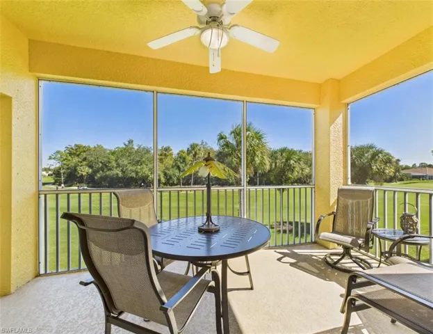 Sunroom featuring a textured wall, a balcony, a ceiling fan, and carpet floors