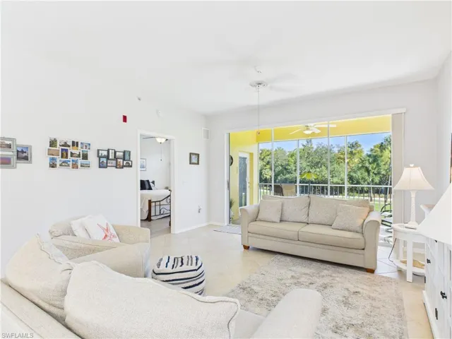 Living room with ceiling fan and light tile patterned flooring