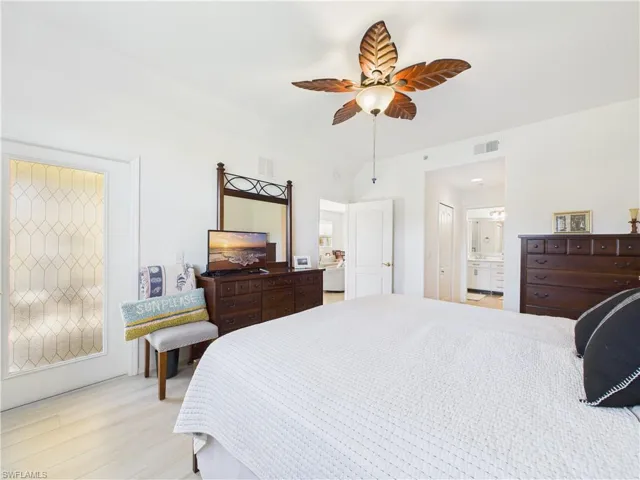 Bedroom with light wood-style flooring, a ceiling fan, and ensuite bath