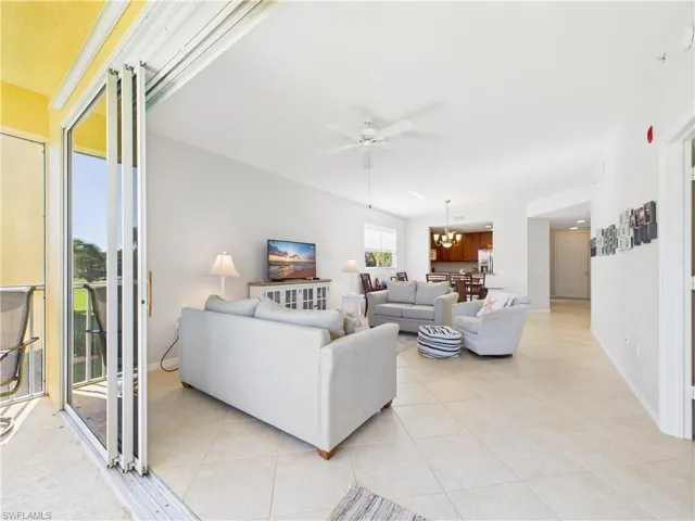 Living room with light tile patterned floors, ceiling fan, and a chandelier