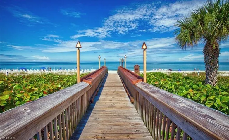 View of community featuring view of water and beach and a pier
