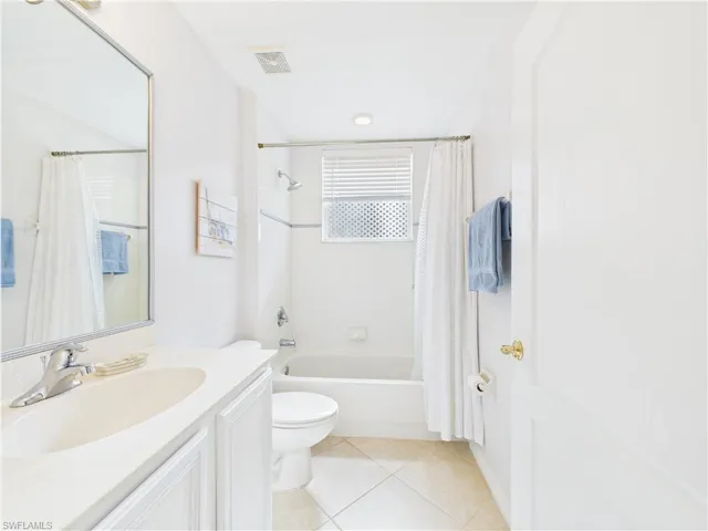 Full bathroom featuring shower / bath combo with shower curtain, vanity, and light tile patterned floors