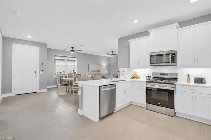 Kitchen with appliances with stainless steel finishes, sink, and white cabinets