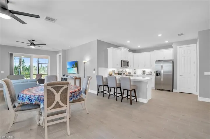 Dining space with sink, ceiling fan, and light wood-type tile flooring