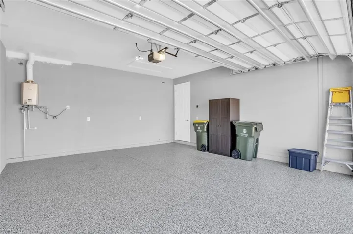 Garage with water heater, garage door opener, and epoxy flooring