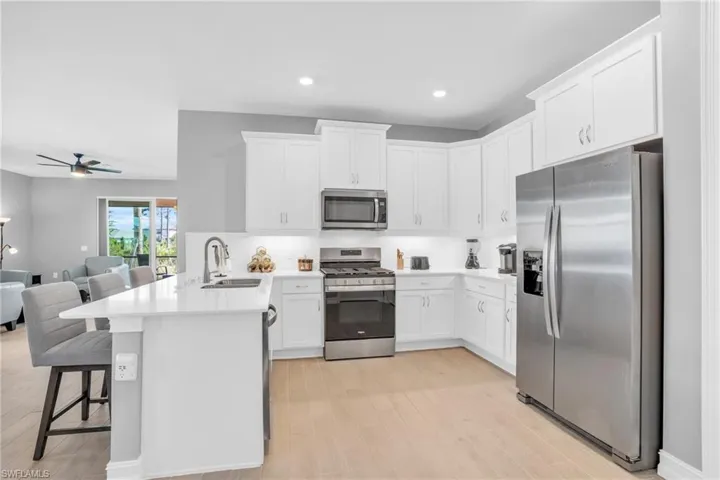 Kitchen featuring sink, appliances with stainless steel finishes, white cabinetry, and kitchen bar