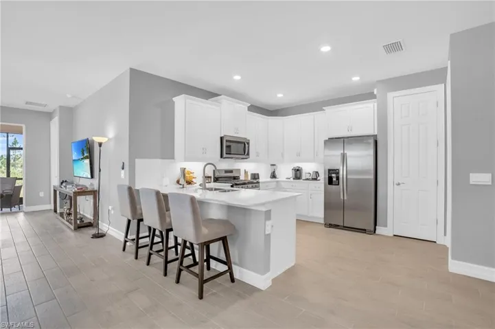 Kitchen featuring appliances with stainless steel finishes, sink, a breakfast bar area with white cabinets