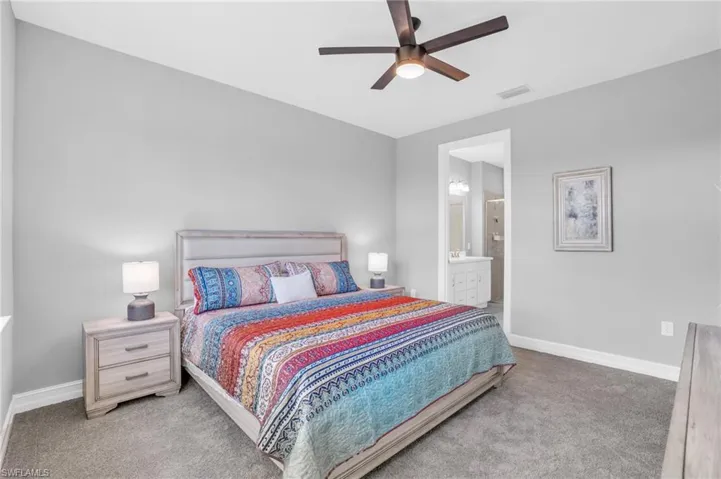Carpeted bedroom featuring ceiling fan and ensuite bath