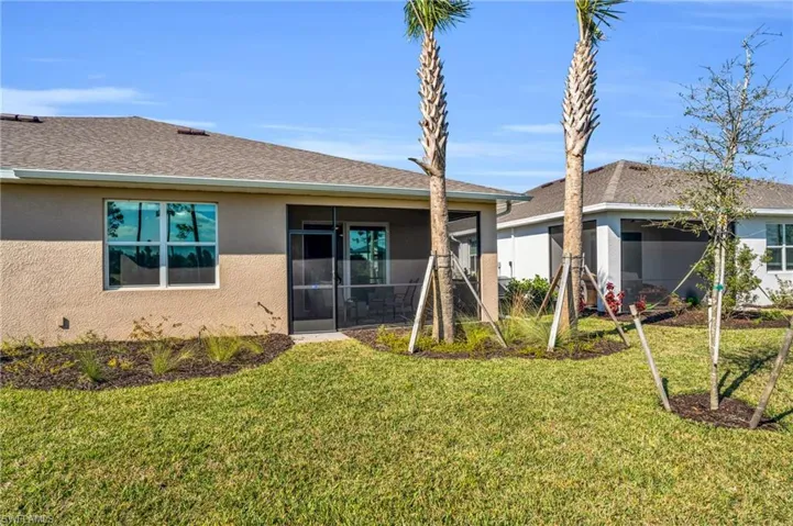 Rear view of property with a lanai and a lawn