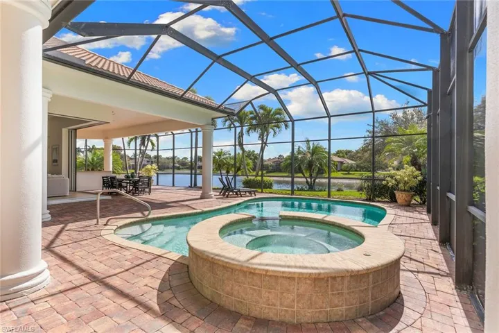 Integrated pool / spa featuring a sunroom, a patio, glass enclosure, and a water view