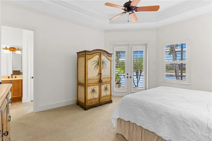 Bedroom featuring access to outside, a ceiling fan, light colored carpet, french doors, and crown molding