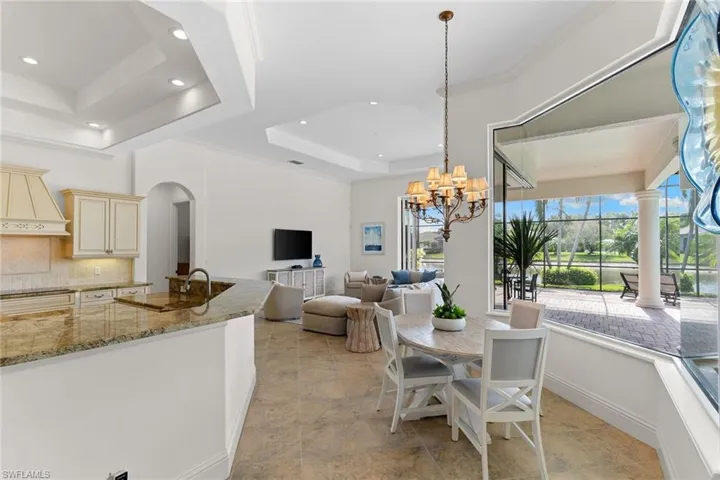 Dining space with a tray ceiling, arched walkways, and a chandelier
