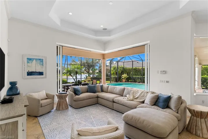 Living room featuring a sunroom, ornamental molding, a raised ceiling, and recessed lighting