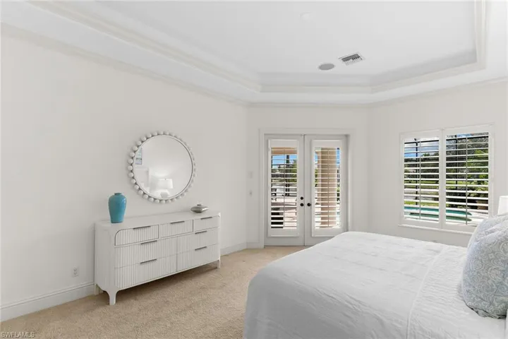 Bedroom featuring french doors, access to outside, light carpet, crown molding, and a raised ceiling