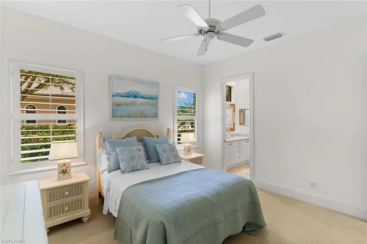 Bedroom featuring light colored carpet, ensuite bathroom, and ceiling fan
