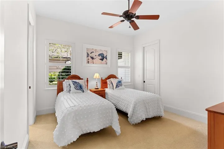Carpeted bedroom with ceiling fan and a closet