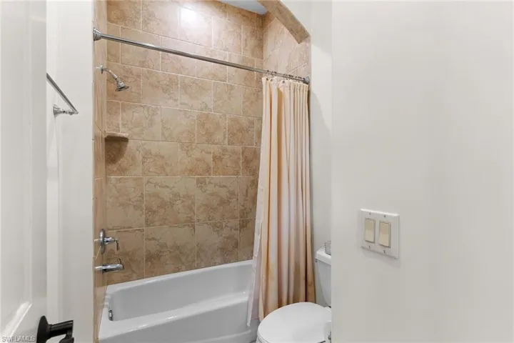 Full bathroom featuring toilet and shower / tub combo with curtain