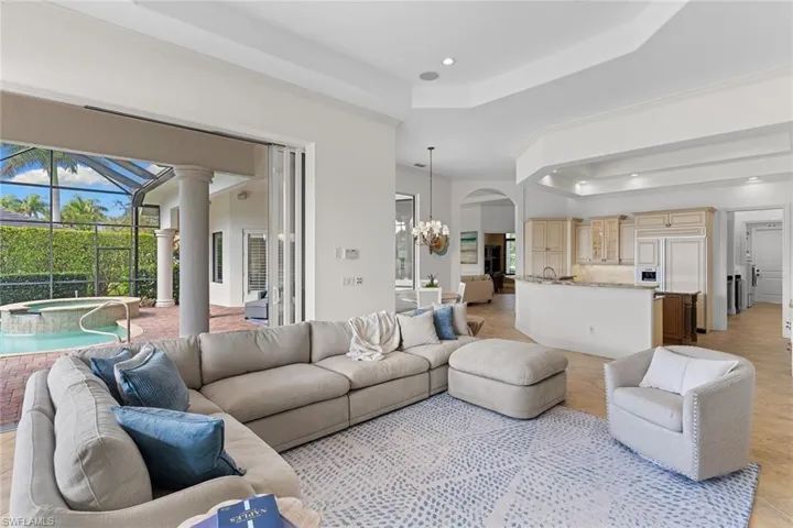 Living room featuring a tray ceiling, a sunroom, and suspended lighting