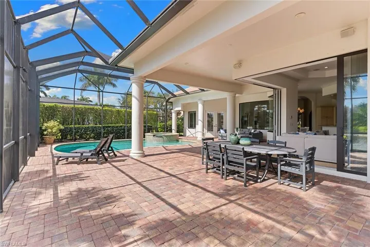 View of patio with outdoor dining area, a sunroom, glass enclosure, and a pool with connected hot tub