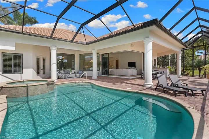 Combined pool / hot tub featuring a sunroom, glass enclosure, a patio area, and an outdoor kitchen
