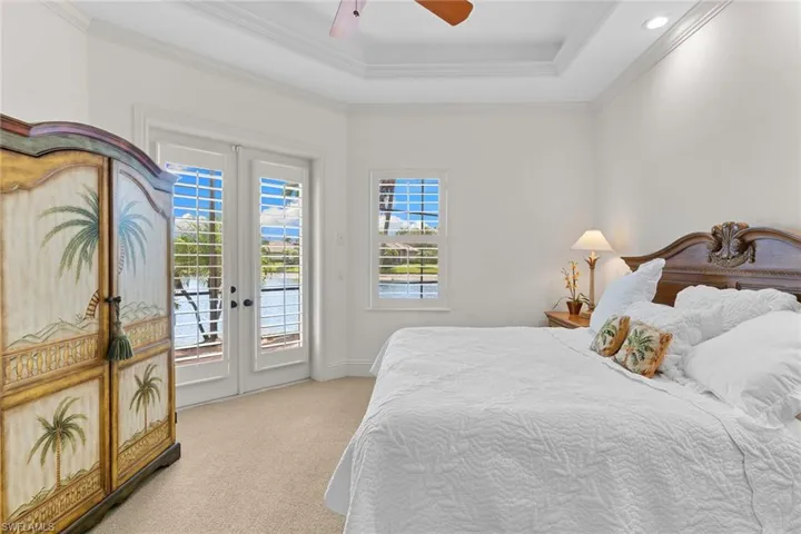 Bedroom with access to outside, a ceiling fan, light carpet, ornamental molding, and french doors