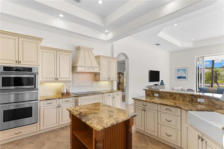 Kitchen with cream cabinets, a raised ceiling, arched walkways, a warming drawer, and stainless steel oven