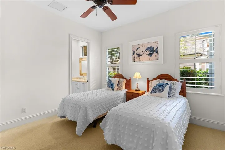 Carpeted bedroom featuring multiple windows and a ceiling fan