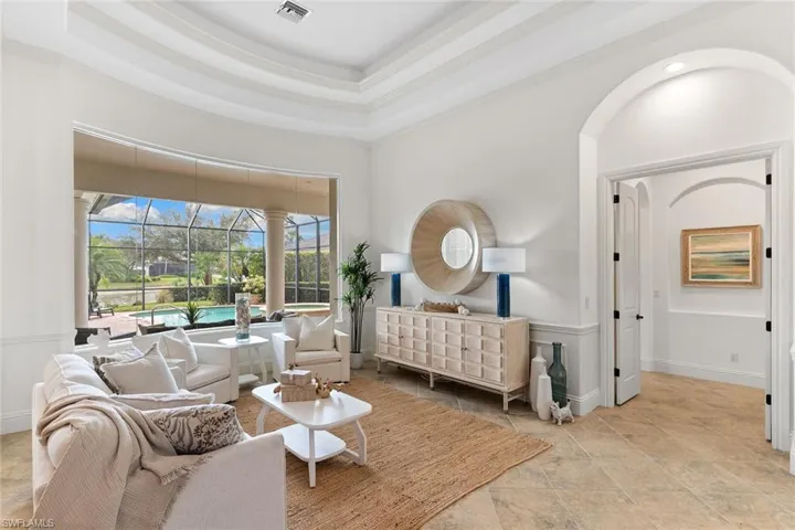 Bedroom with a sunroom, a raised ceiling, ornamental molding, and light stone finish flooring