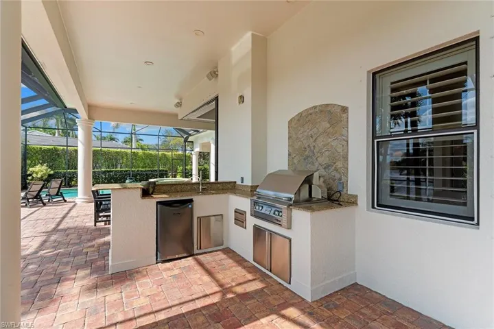 View of patio featuring exterior kitchen, a sunroom, and a lanai